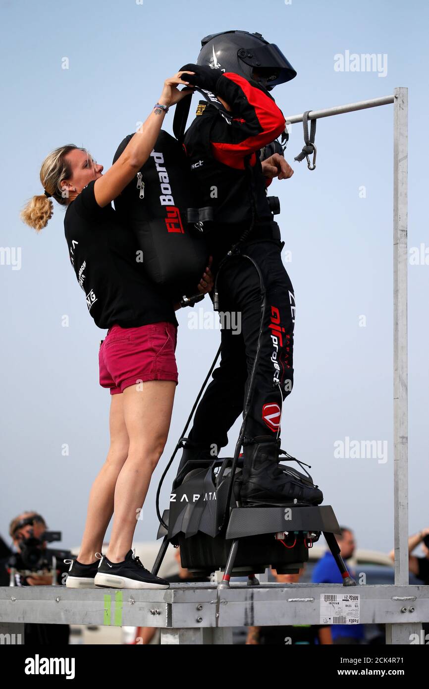 El inventor francés Franky Zapata en un Flyboard es ayudado por su esposa  para instalar una bolsa de suministro de combustible en su espalda durante  una manifestación mientras se prepara para cruzar