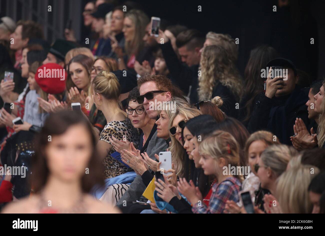 Los actores Damian Lewis y su esposa Helen McCrory (C) observan un modelo durante el espectáculo Temperley London en London Fashion Week, Londres, Gran Bretaña, 18 de febrero de 2018. REUTERS/Paul Hackett Foto de stock