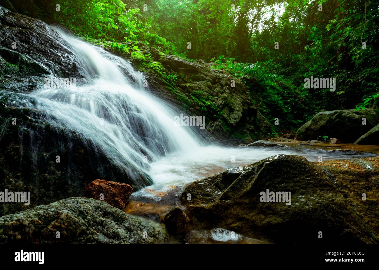 Hermosa cascada en la selva. Cascada en el bosque tropical con árboles verdes y luz solar. La cascada fluye en la selva. Naturaleza de fondo. Rock. Foto de stock