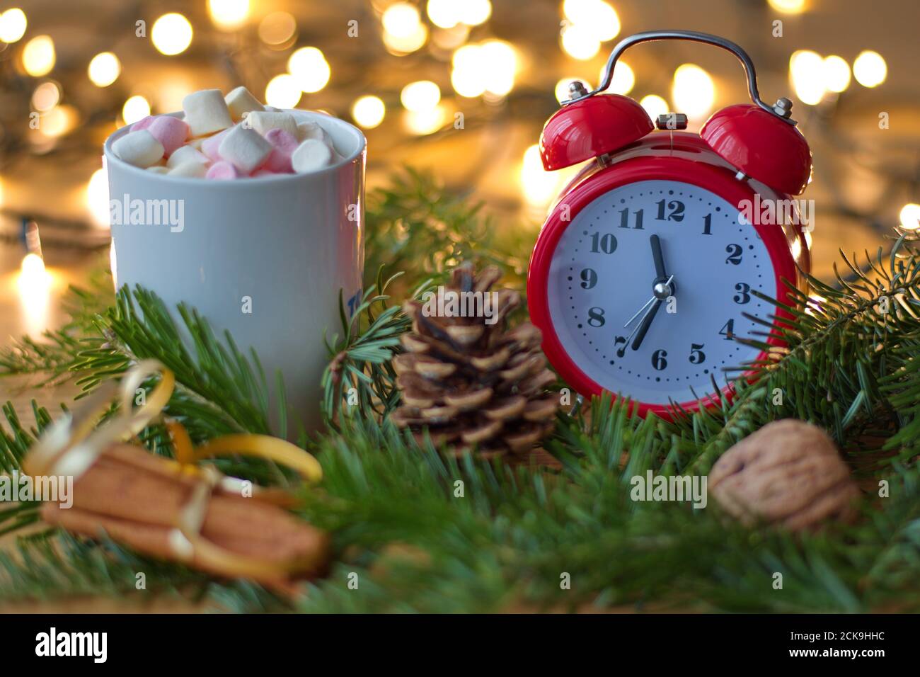 Adornos de Navidad y reloj rojo en la mesa con cono de pino, canela, frutos  secos y taza de café con malvaviscos - bokeh luces en el fondo Fotografía  de stock - Alamy
