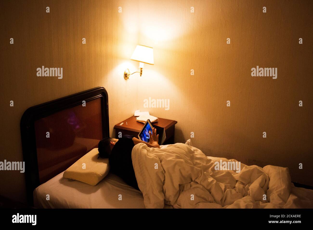 Huang Wensi mira su iPad mientras está en la cama incapaz de dormir, lo que  atribuye a haber bebido té de leche para celebrar su victoria en Taipei,  Taiwán, 27 de septiembre