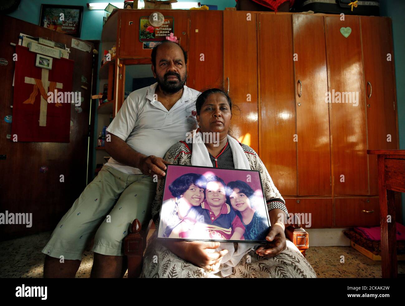 Karibeeran Paramesvaran y su esposa Choodamani, que habían perdido a tres hijos en el tsunami de 2004, posan con una fotografía que muestra a sus hijos dentro de su casa que se han convertido en un hogar de cuidado para niños huérfanos en el distrito de Nagapattinam, en el estado sureño de Tamil Nadu, India, el 4 de diciembre de 2019. Foto tomada el 4 de diciembre de 2019. REUTERS/P. Ravikumar Foto de stock