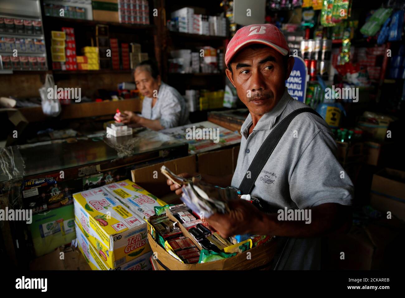 Un vendedor callejero cuenta dinero mientras compra una caja de cigarrillos  suaves producidos por PT HM Sampoerna en una tienda de cigarrillos en  Yakarta, 1 de agosto de 2017. REUTERS/Beawiharta Fotografía de