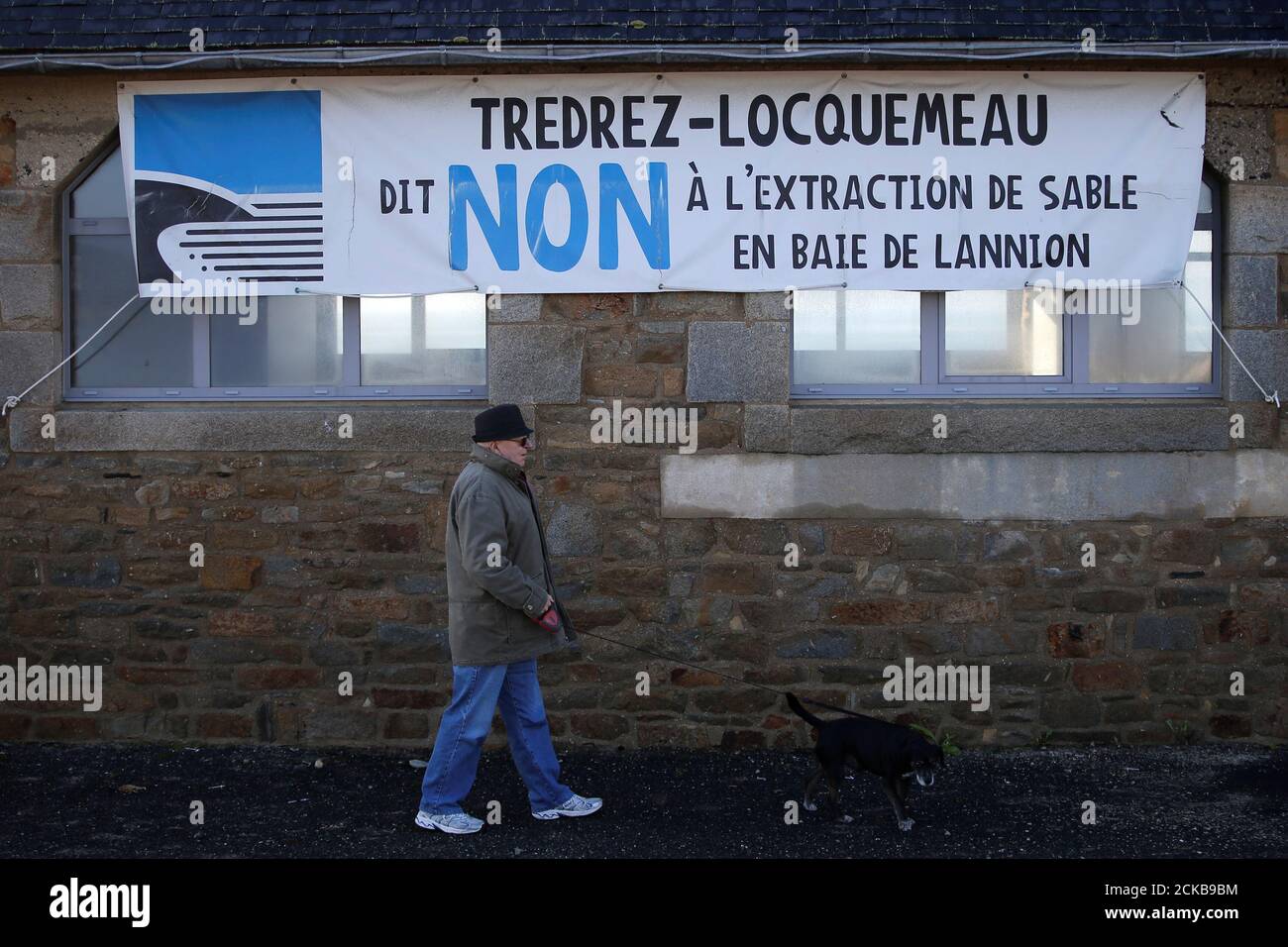 A man walks in front of a banner which reads: "Tredrez-Locquemeau say No to the extraction of sand in the bay of Lannion" in Tredrez-Locquemeau, December 17, 2016. REUTERS/Stephane Mahe Foto de stock