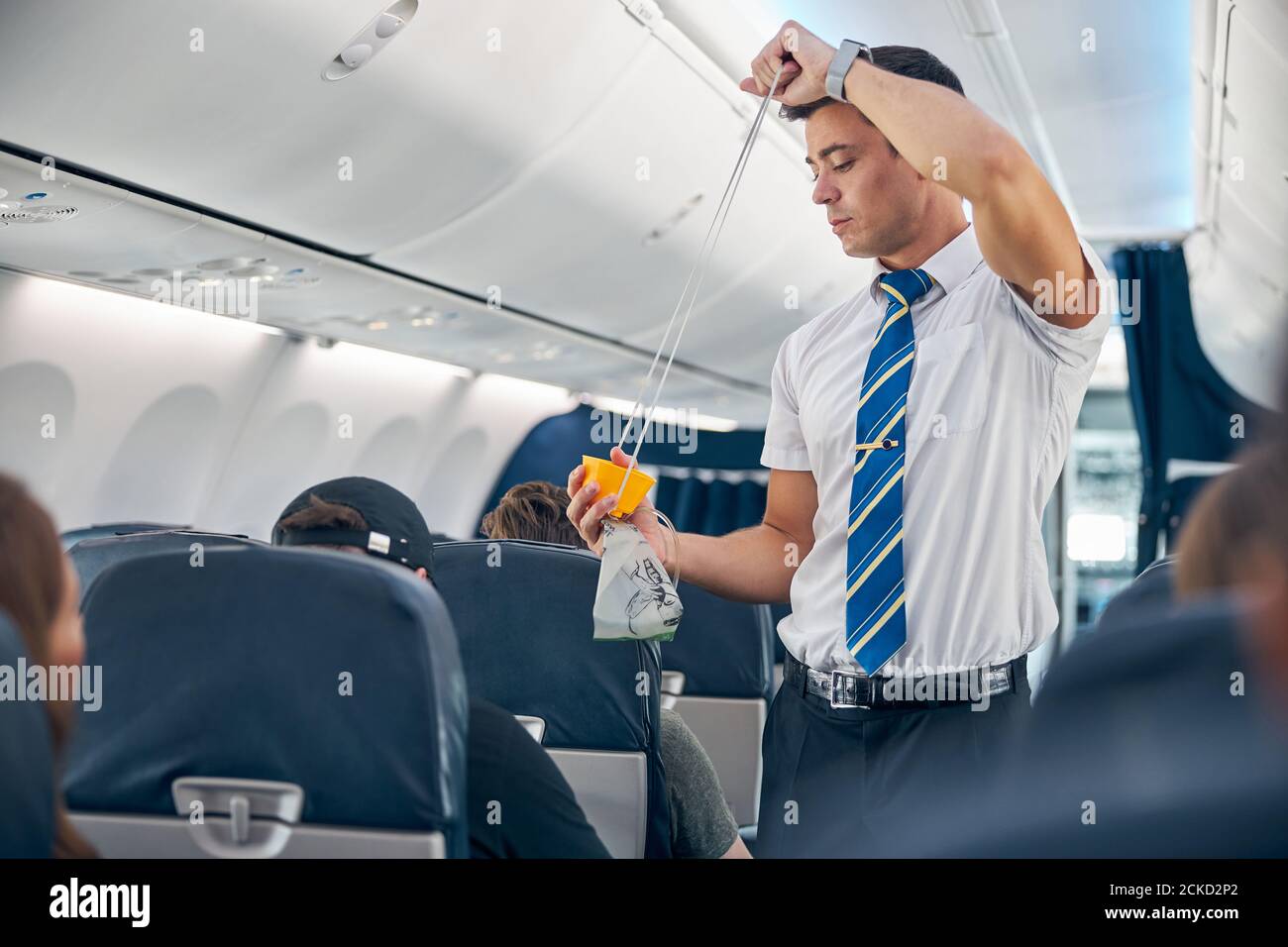 del mayordomo en el avión de pasajeros de cabina que instruye a los pasajeros sobre de seguridad en de emergencia Fotografía de stock -