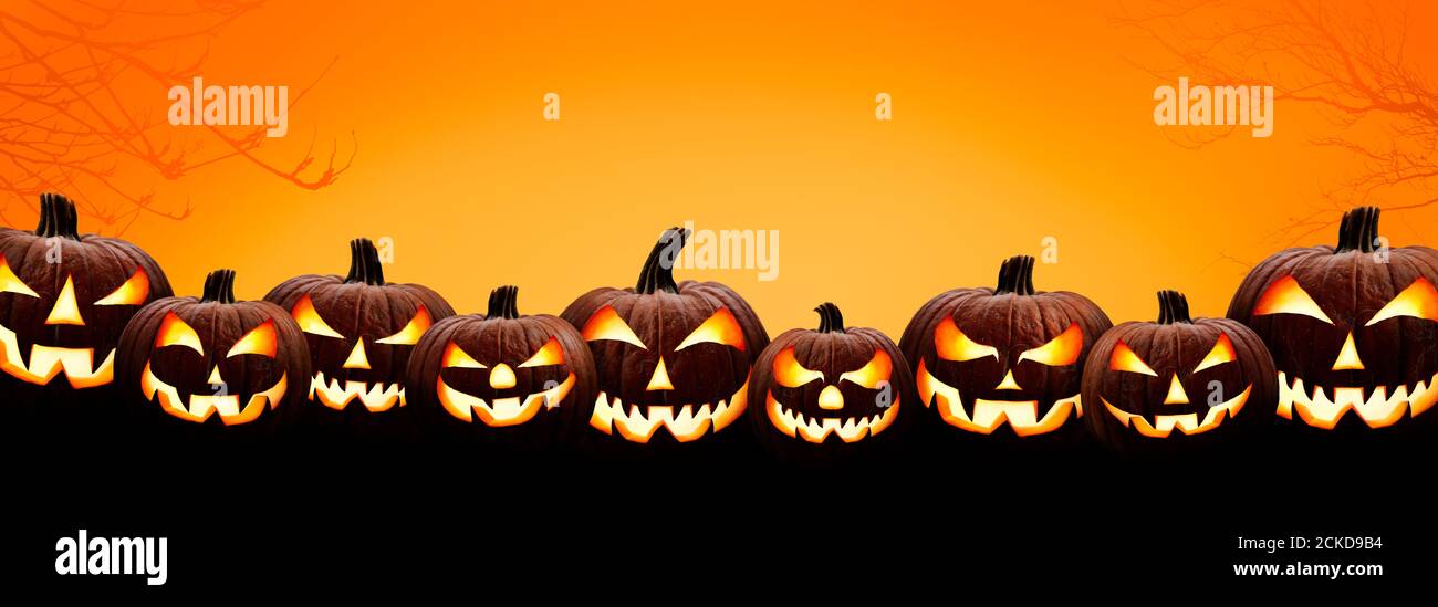 Nueve halloween, Jack o Lanterns, con los ojos y las caras malvados y espeluznantes aislados contra un fondo naranja y amarillo iluminado. Foto de stock