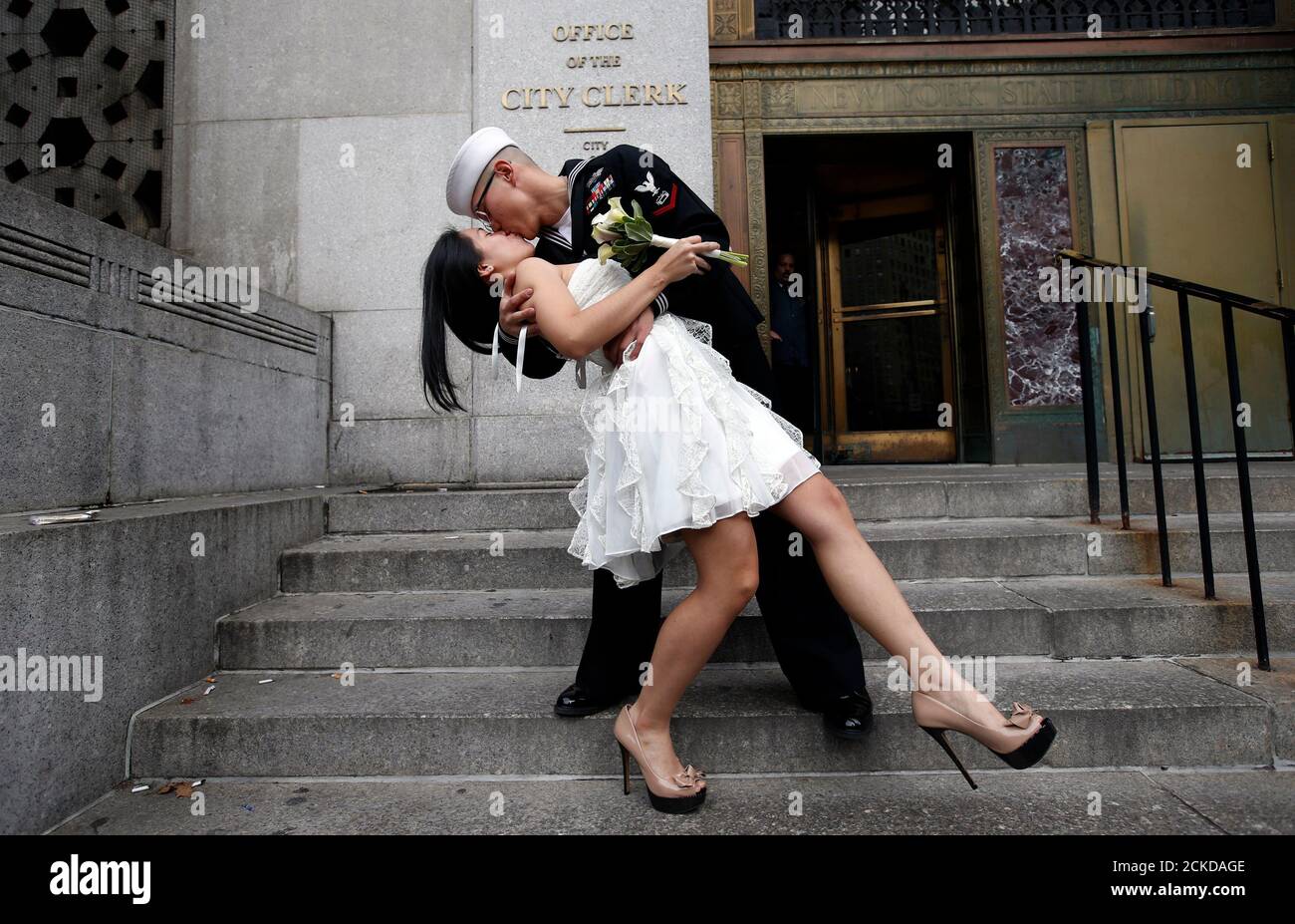 Oficial de Petty de la Marina de los EE.UU. 3rd Class EO3 John Chen, 23, de Lakehurst, Nueva Jersey, besa a su nueva novia Victoria Chan, 25, de Manhattan, mientras posan para los fotógrafos después de que se casaron en una ceremonia civil en la Oficina del Secretario de la Ciudad de Nueva York el 12 de diciembre de 2012. Cientos de parejas empaquetaron la oficina en el bajo Manhattan para casarse en la fecha 12/12/12 ya que esta será la última fecha triple de casi un siglo hasta el 1 de enero de 2101. REUTERS/Mike Segar (ESTADOS UNIDOS - Tags: SOCIEDAD RETRATO) Foto de stock