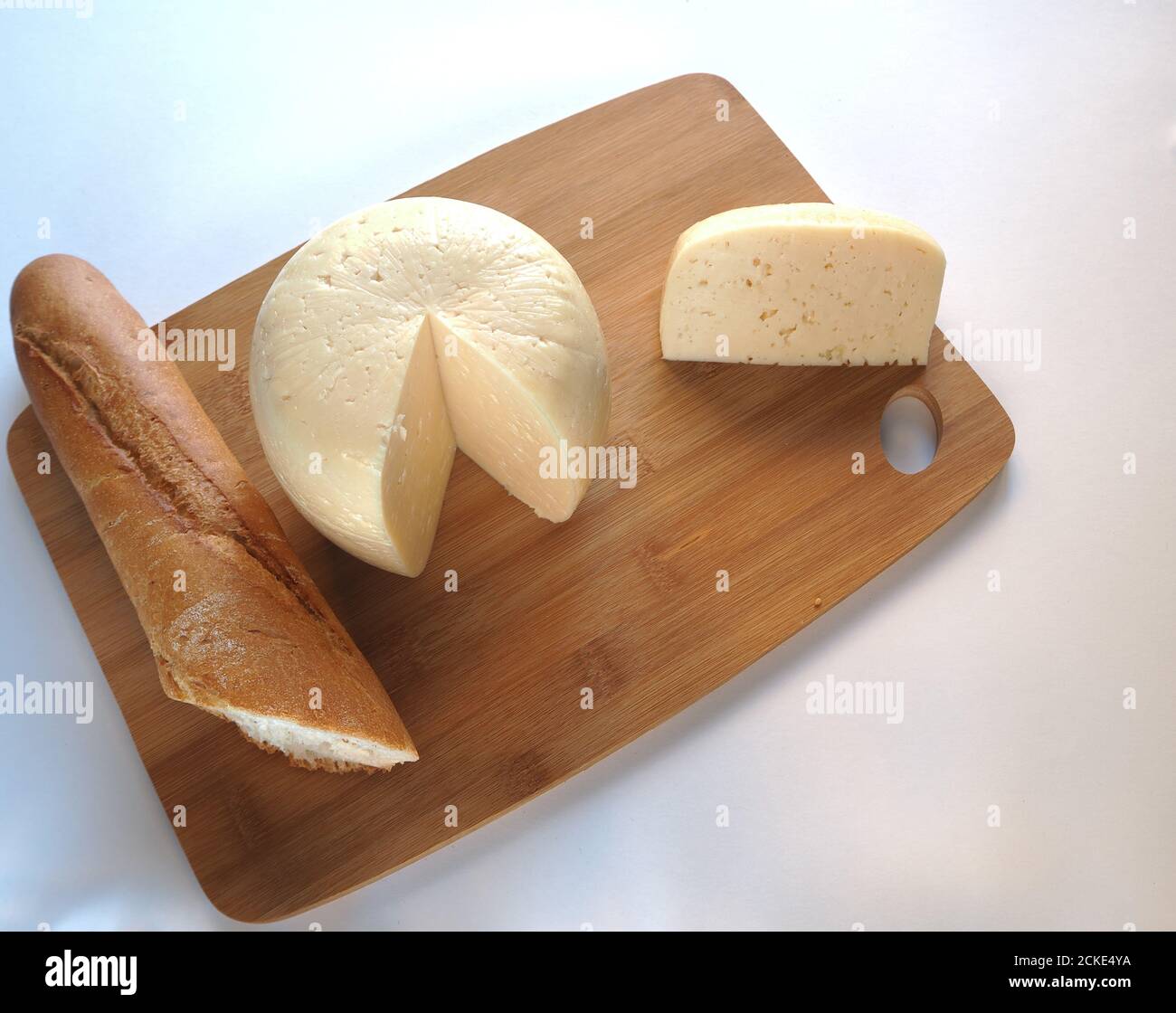Cabeza redonda de queso con una baguette en un primer plano de madera. Fotografía de alta calidad. Foto de stock