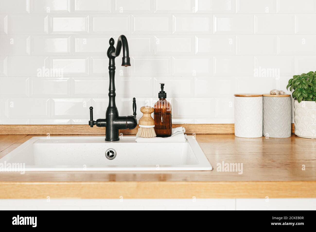 Vista ampliada de un fregadero de cocina blanco con un elegante grifo  plateado actualmente en la posición on