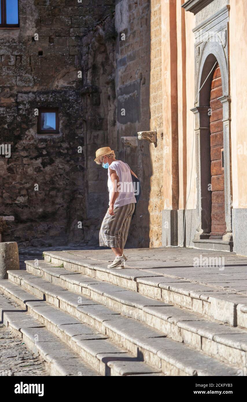 Civita Bagnoregio, 04 de septiembre de 2020 : turista típico con una máscara médica camina en el cementerio de la catedral de Civita di Bagnoregio Foto de stock
