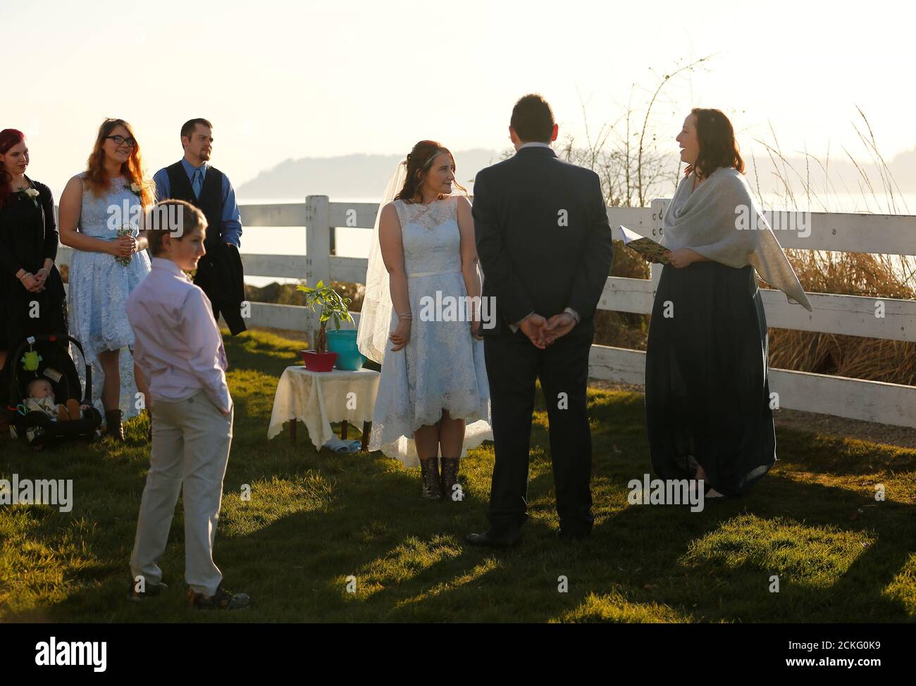 Benji Mincy y Matt Friedman escuchan al oficiante Leah Hausman durante una ceremonia de boda mucho más pequeña de lo planeado debido al brote de la enfermedad del coronavirus (COVID-19) en Mukilteo, Washington, EE.UU. 20 de marzo de 2020. La pareja había planeado una gran celebración de boda de fin de semana en la cercana Whidbey Island, pero eligió tener una pequeña ceremonia que viven en directo a aquellos que no podían venir, incluyendo a la madre de Mincy. REUTERS/Lindsey Wasson Foto de stock