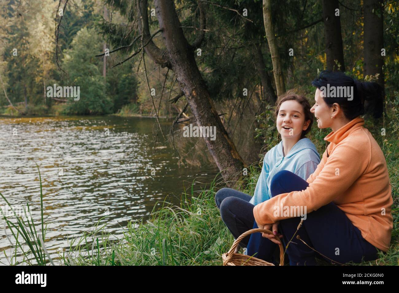 Concepto de familia. Chica sonriente hablando con su madre. Recreación al aire libre con niños. Foto de stock