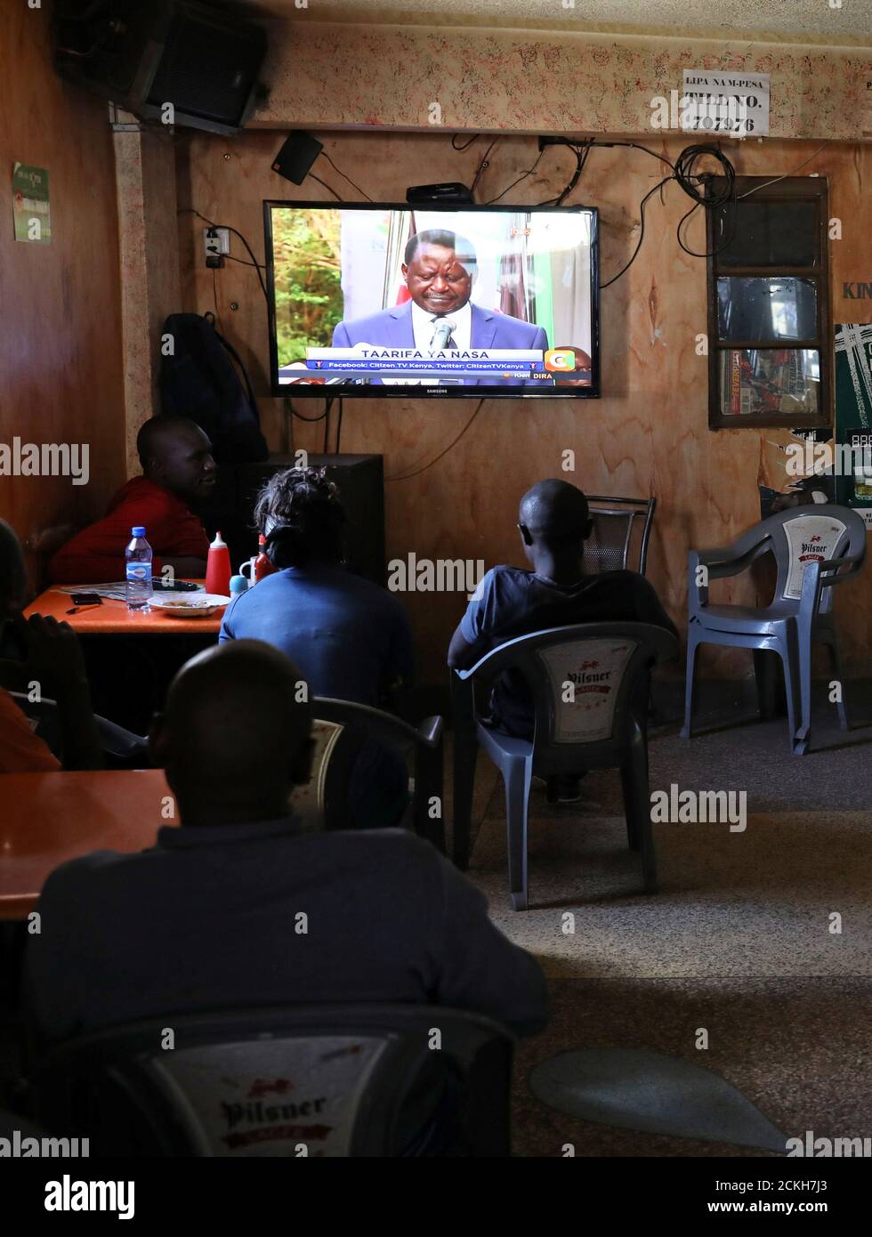 Las personas que se sientan en un bar en el barrio marginal de Mathare observan la conferencia de prensa de Raila Odinga, líder de la oposición keniata de la coalición de la Super Alianza Nacional (NASA), que se celebrará en Nairobi, Kenia, el 31 de octubre de 2017. REUTERS/Siegfried Modola Foto de stock