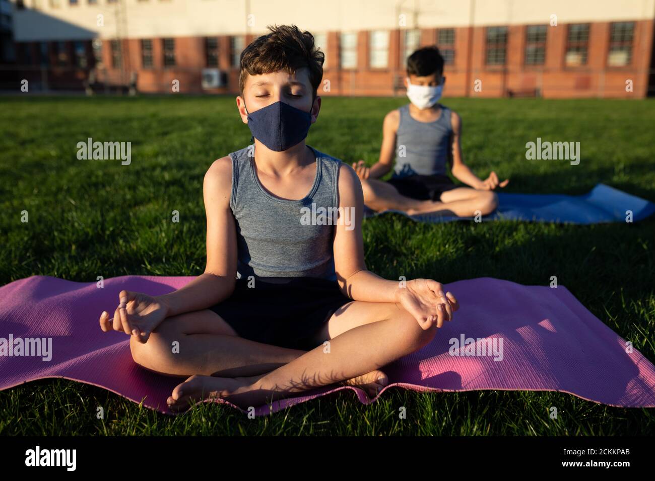 Niño con máscara facial haciendo yoga en el jardín Foto de stock