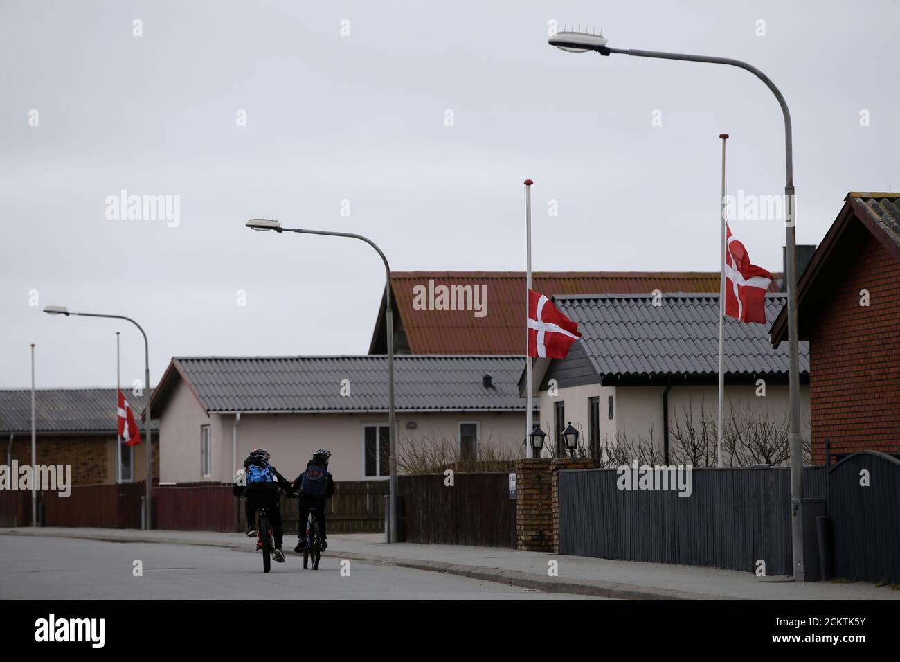 Los niños pasan junto a una hilera de banderas danesas a media asta, voladas con respecto a un residente que falleció en la aldea de Thyboron en Jutlandia, Dinamarca, el 21 de marzo de 2019. REUTERS/Andrew Kelly Foto de stock