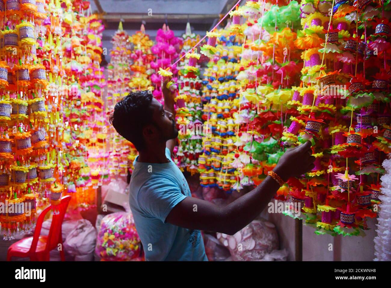 La gente está arreglando guirnaldas para la venta hechas de diferentes  tipos de plástico en una fábrica de guirnaldas, antes de la Durga Puja en  las afueras de Agartala, Tripura, India Fotografía