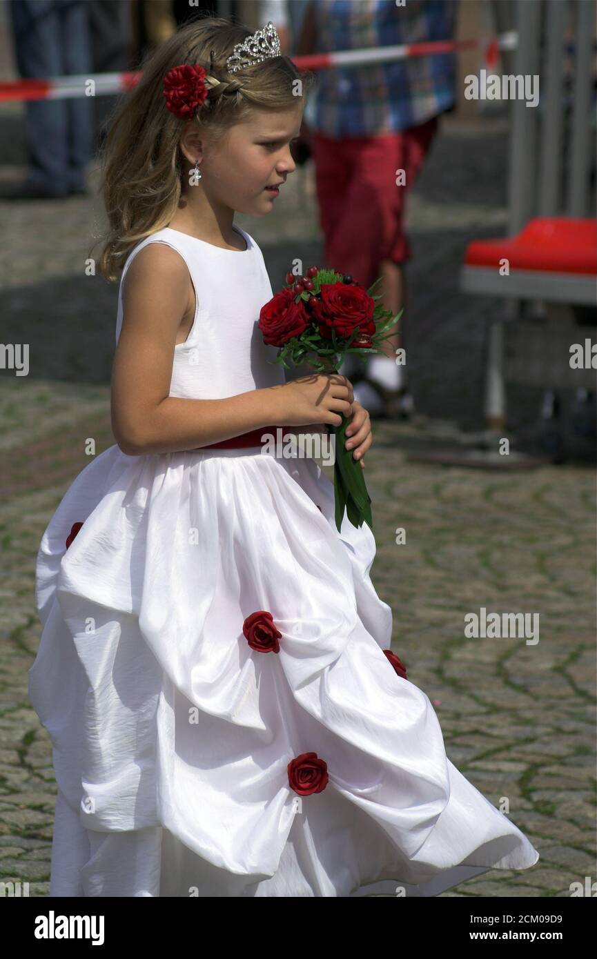 Niña en un hermoso vestido blanco y un ramo de flores en la mano. Das Mädchen in einem schönen weißen Kleid und einem Blumenstrauß. Dziewczynka Foto de stock