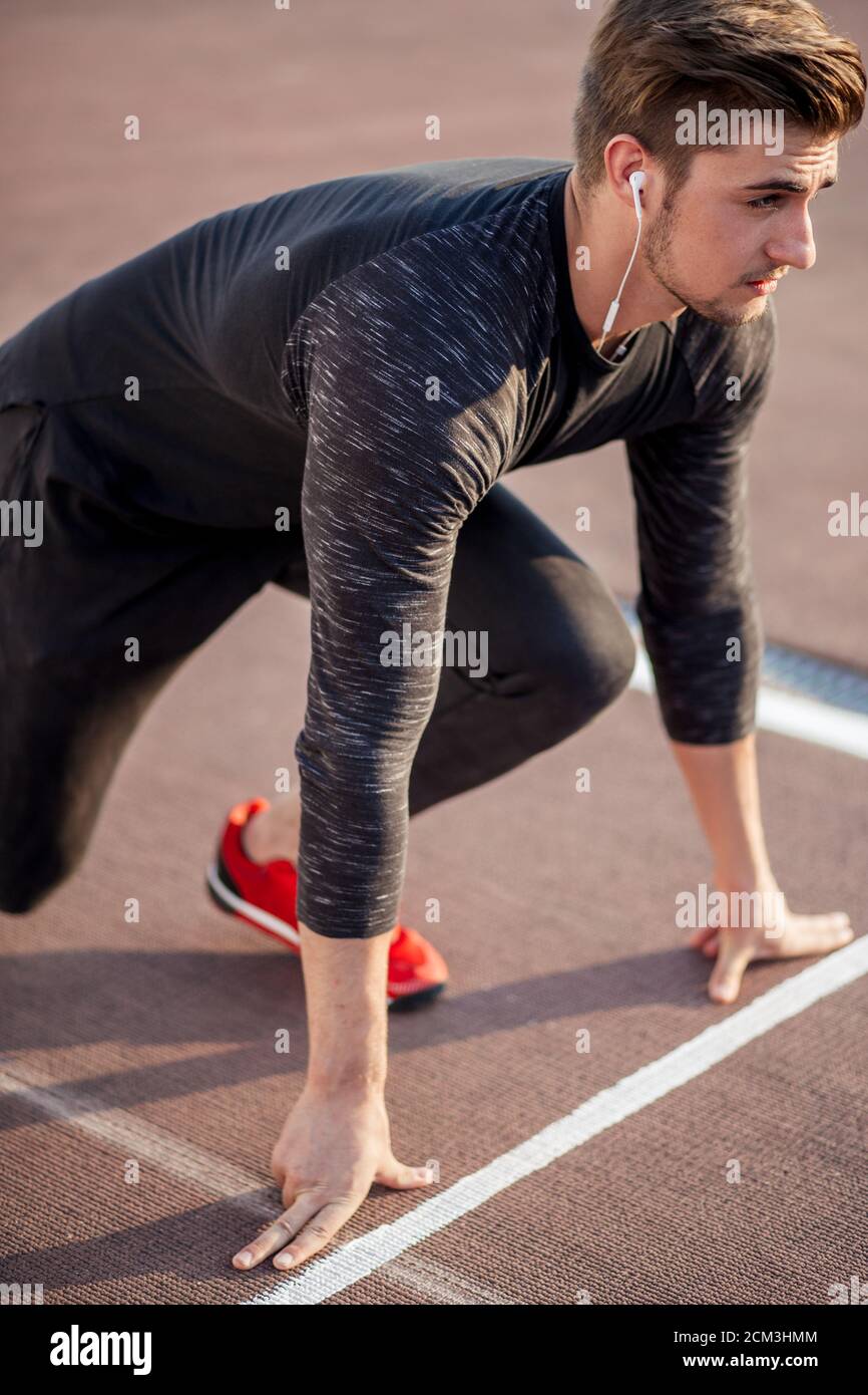 Sanción sufrir hogar Joven vistiendo ropa negra y zapatos rojos en la posición inicial para  correr en pista en el estadio de deportes Fotografía de stock - Alamy