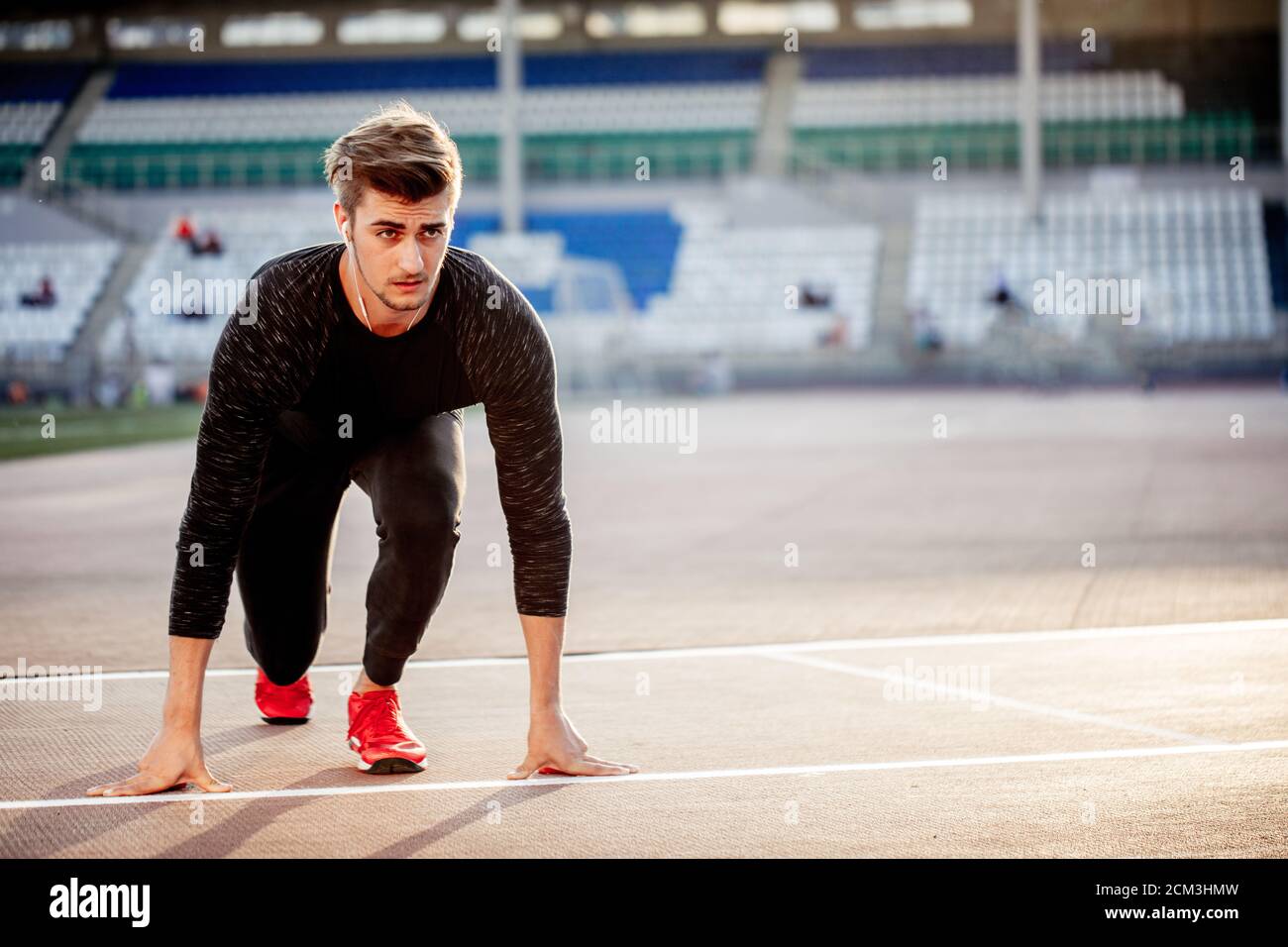 Sanción sufrir hogar Joven vistiendo ropa negra y zapatos rojos en la posición inicial para  correr en pista en el estadio de deportes Fotografía de stock - Alamy