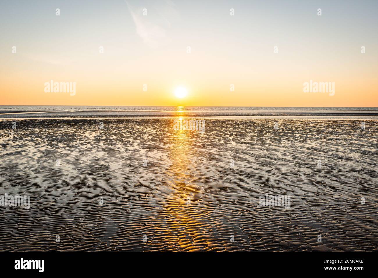 Hermosa puesta de sol en la costa de playa de arena en Dinamarca. Soleado fondo natural. Cielo despejado con sol Foto de stock