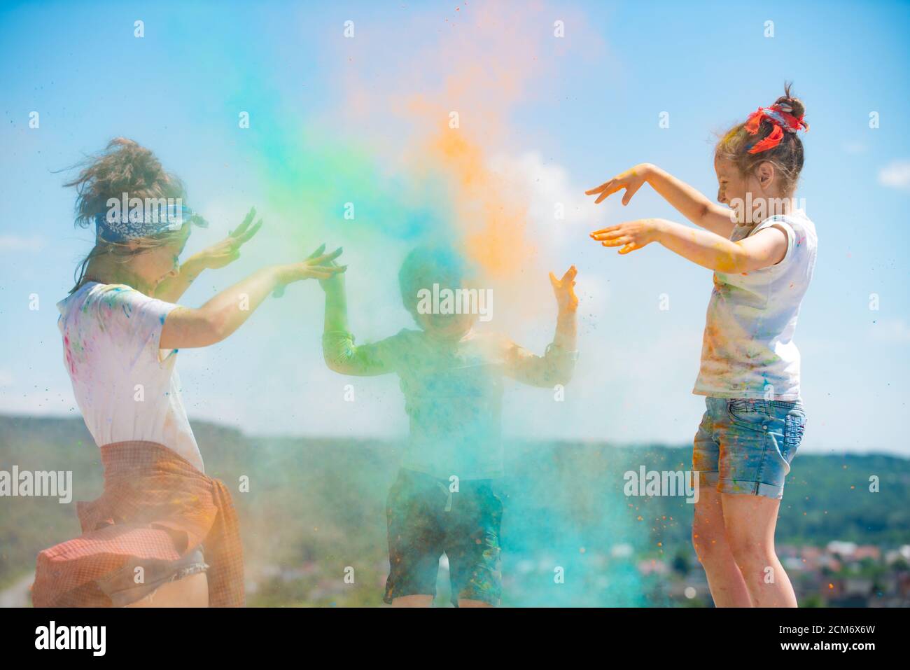 Grupo de niños disfrutando jugando con polvo de colores y salpicaduras de polvo de colores. Foto de stock