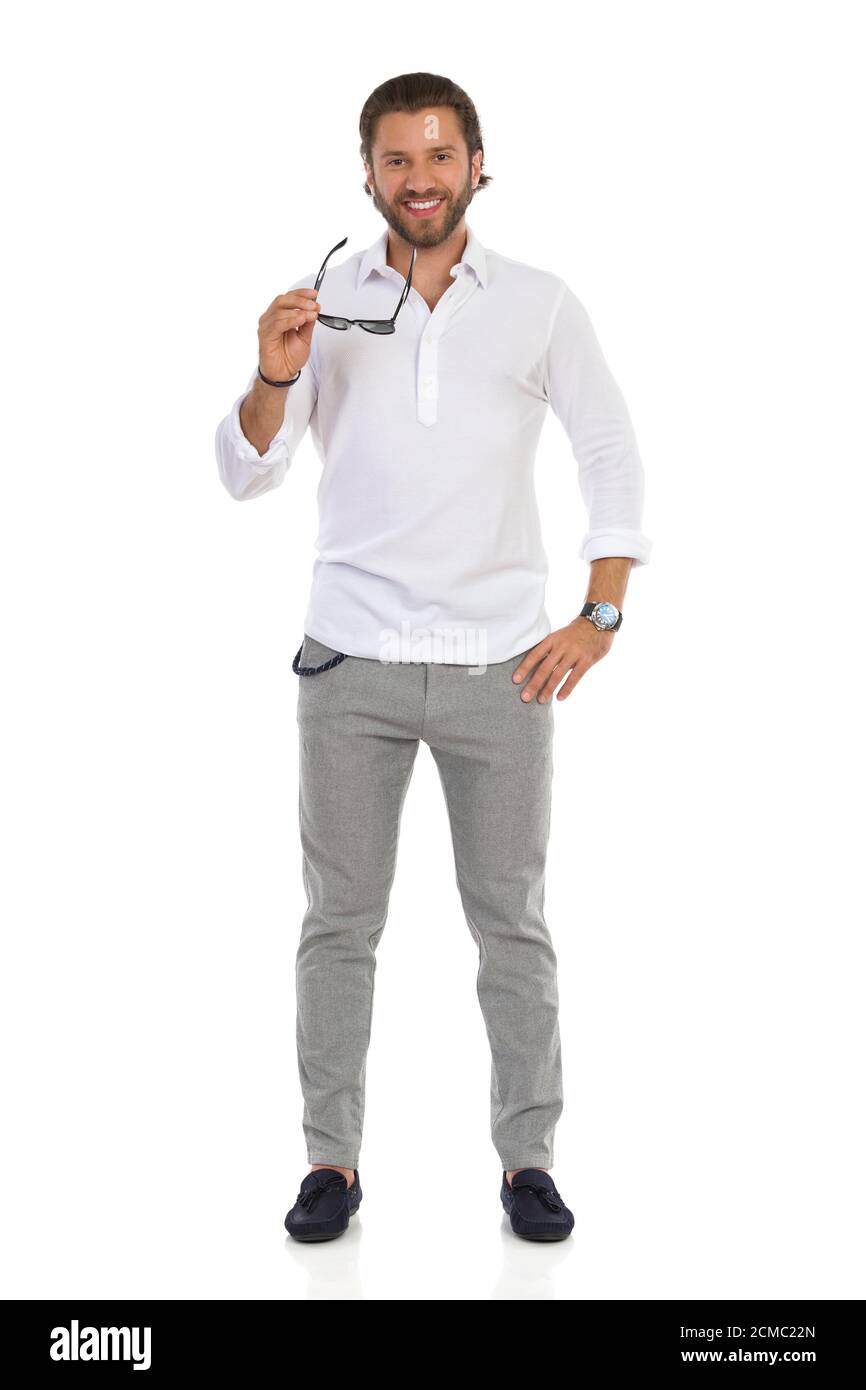 Un joven elegante con camisa blanca, pantalones y mocasines está posando con gafas de sol. Vista frontal. Estudio de duración completa aislado sobre blanco Fotografía de stock - Alamy
