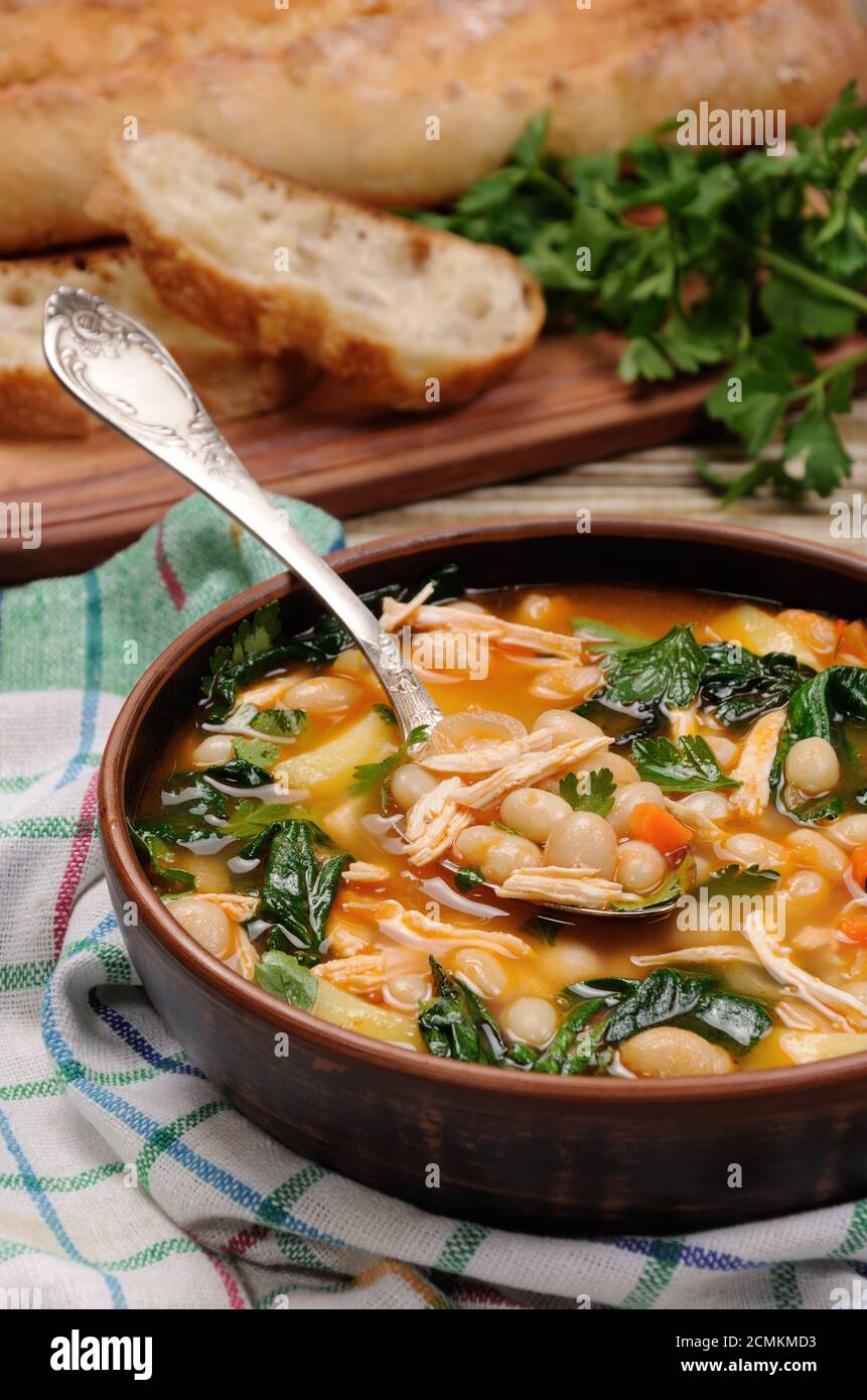 Sopa de pollo con judías blancas, las espinacas y el tomate Fotografía