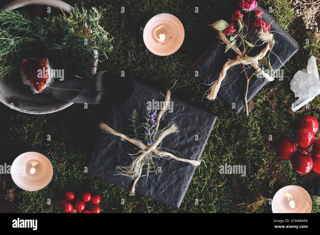 Yule (Navidad) tema plano de la disposición de regalos negros sobre el fondo del bosque de la naturaleza. Humor esotérico oculto de los regalos envueltos en papel de tejido negro Foto de stock