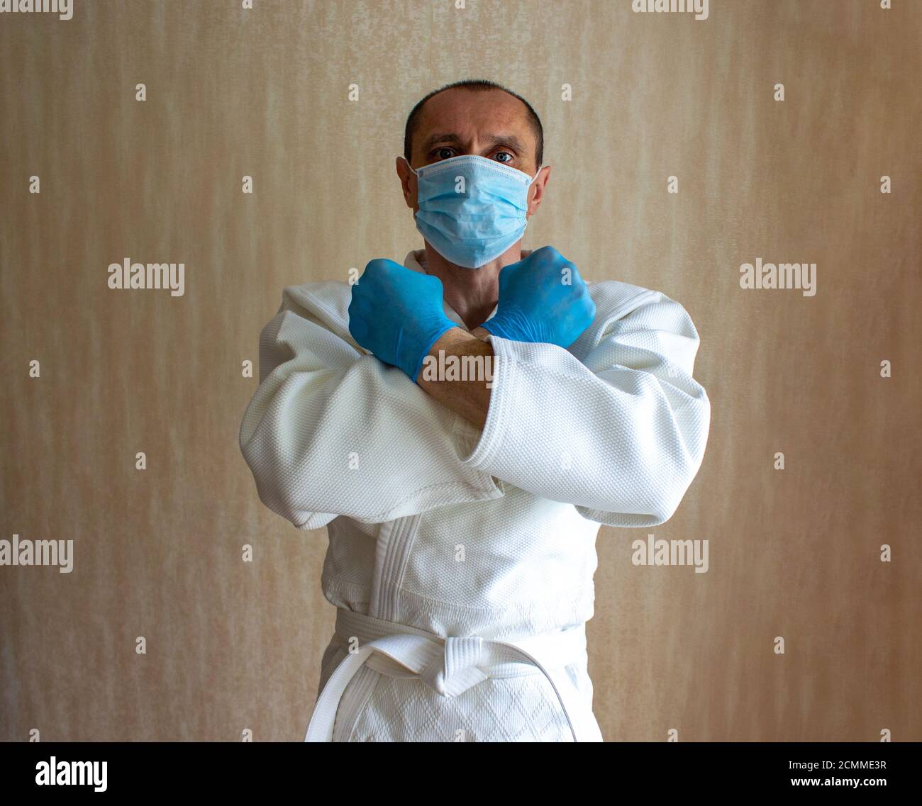 Concepto de coronavirus pandémico COVID-19. Un joven hombre fuerte en un  kimono blanco para sambo, jiu jitsu y otras artes marciales con un azul  guantes médicos y Fotografía de stock - Alamy