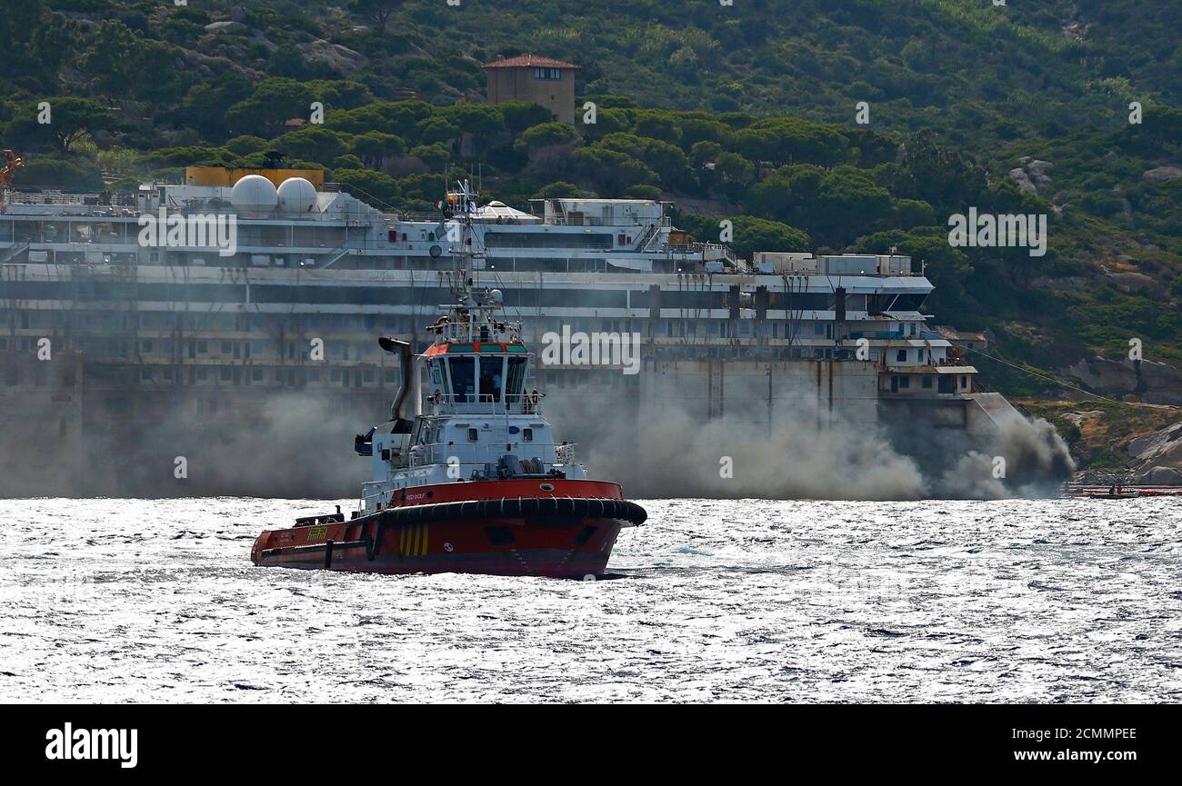 Black smoke comes out from the back of the Costa Concordia cruise liner during its refloat operation at Giglio harbour July 22, 2014. The massive hulk of the Costa Concordia is nearly ready to be towed away from the Italian island where it struck a rock and capsized two-and-a-half years ago, killing 32 people, officials said on Sunday. The 114,500-tonne Concordia has been slowly lifted from the sea floor since Monday, when salvagers began pumping air into 30 large metal boxes, or sponsons, attached around the hull. A convoy of 14 vessels will then tow the Concordia to a port near Genoa, where Foto de stock