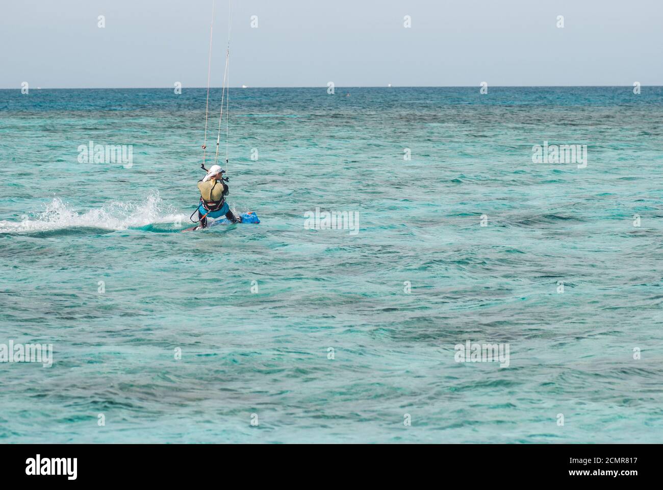 Kiter profesional se deslizan en la superficie del agua del océano a gran velocidad. Vista posterior detrás de gran angular Foto de stock