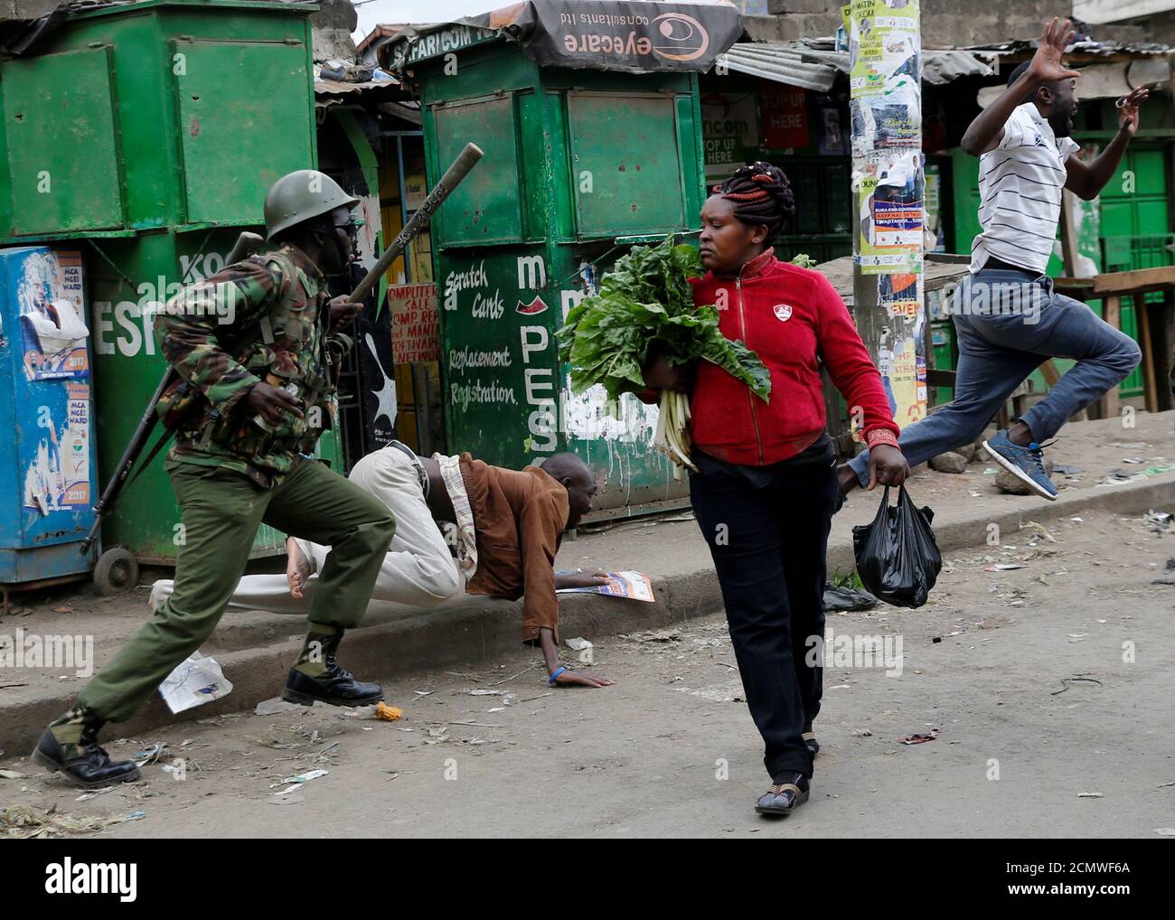 Un policía antidisturbios intenta dispersar a la gente de la calle mientras una mujer que lleva verduras camina por Mathare, en Nairobi, Kenia, 9 de agosto de 2017. REUTERS/Thomas Mukoya IMÁGENES TPX DEL DÍA Foto de stock