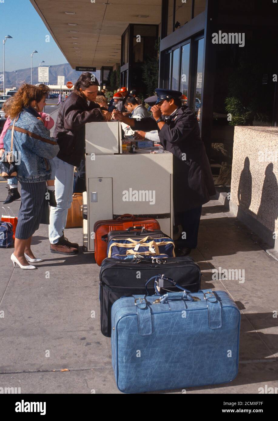 EL PASO, TEXAS, EE.UU., DICIEMBRE 1992 - las se alinearon en la acera mientras los pasajeros se facturan con los encargados equipaje en el aeropuerto Fotografía de stock - Alamy
