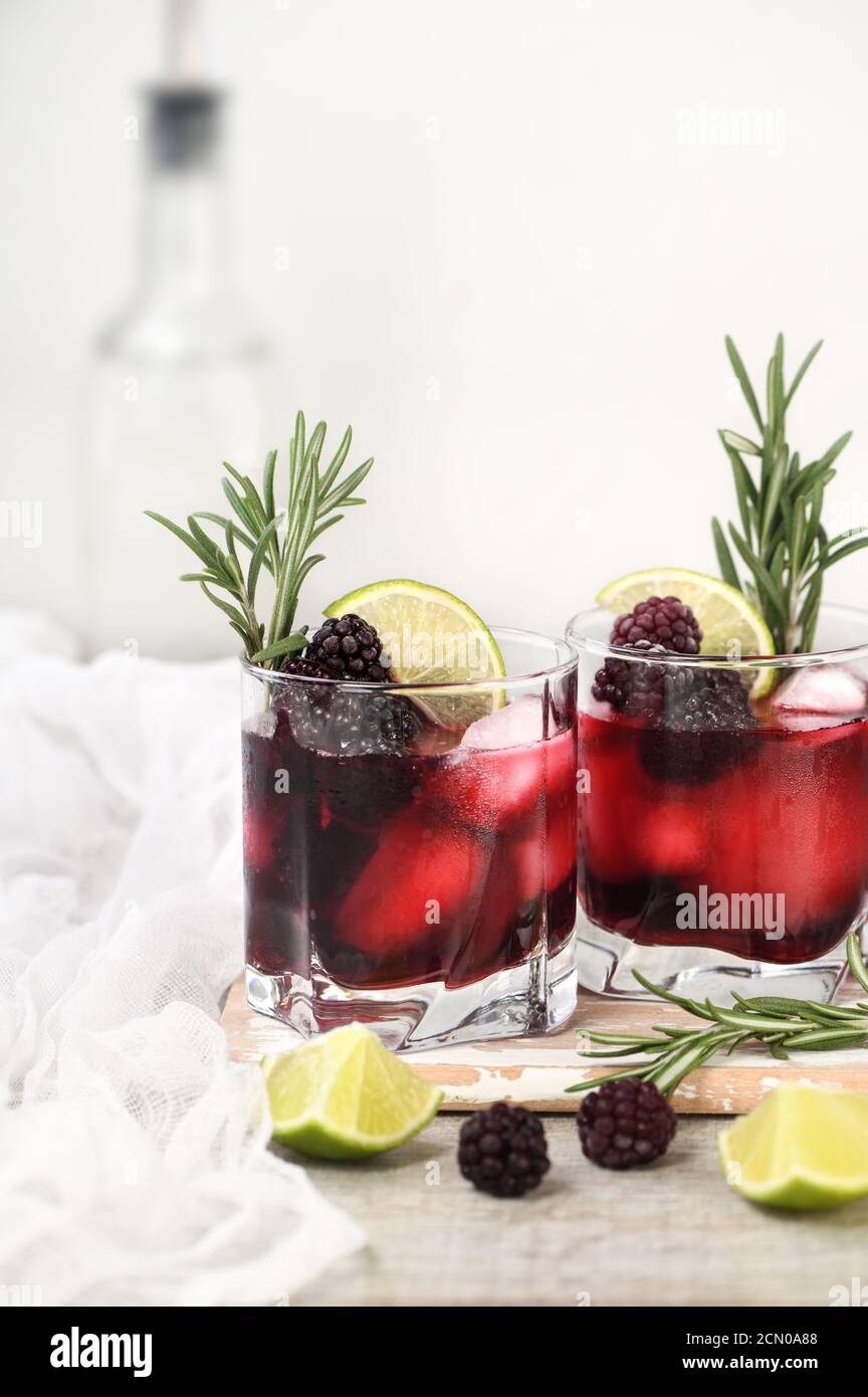 Cóctel alcohólico. Bebida alcohólica fría con hielo, cal, blackberry y Ginebra, decorada con romero. Foto de stock