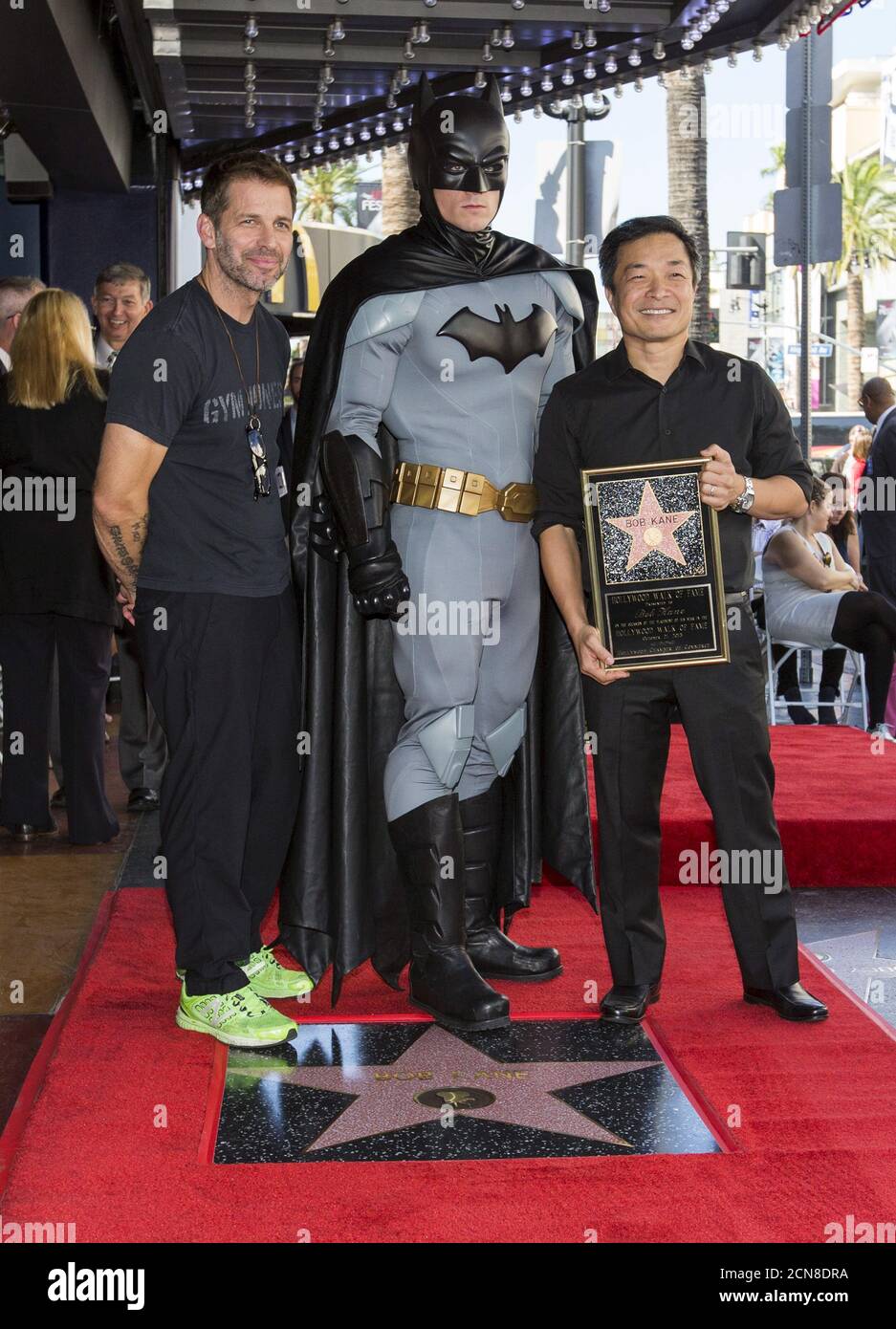 El director Zack Snyder (L) y el coeditor de DC Entertainment Jim Lee posan  con un hombre vestido como Batman después de desvelar póstumamente la  estrella del creador de Batman Bob Kane