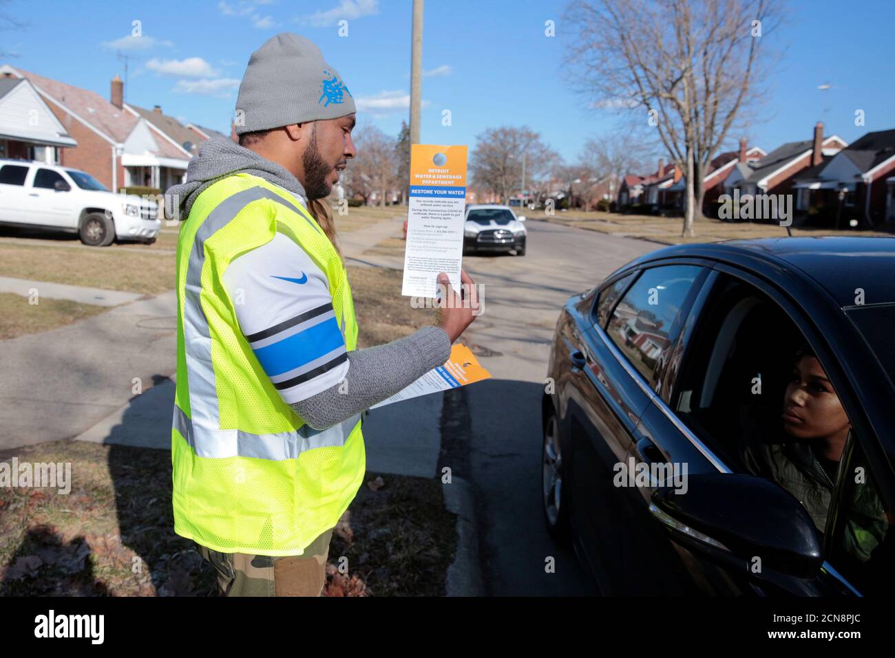 El trabajador por contrato Vaughn Harrington entrega un aviso por el Departamento de agua y Alcantarillado de Detroit para informar a los residentes cómo restaurar el servicio de agua en respuesta al brote de coronavirus en Detroit, Michigan, EE.UU., 13 de marzo de 2020. Foto tomada el 13 de marzo de 2020. REUTERS/Rebecca Cook Foto de stock