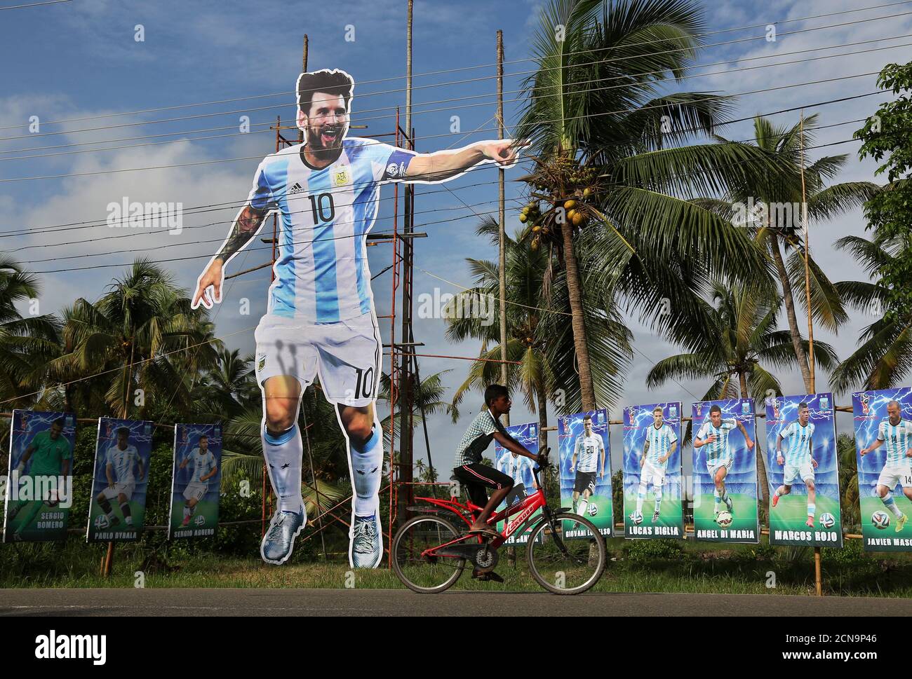 Un niño pasa su bicicleta por un gigantesco jugador de fútbol argentino Lionel Messi en una carretera, antes del encuentro del Grupo D de la Copa Mundial de la FIFA entre