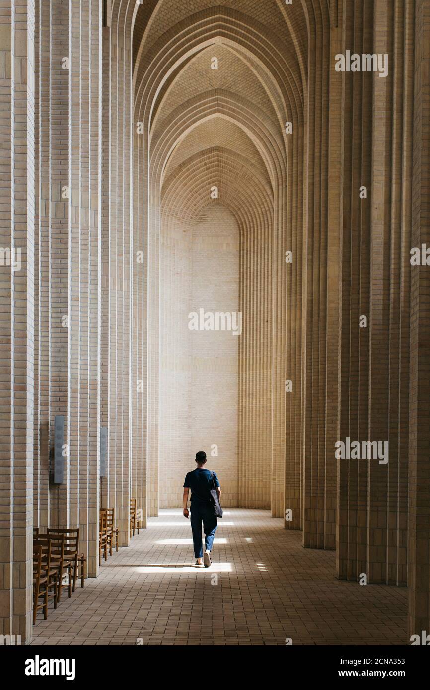 Joven caminando por el claustro, Iglesia Grundtvigs, Copenhague, Dinamarca Foto de stock