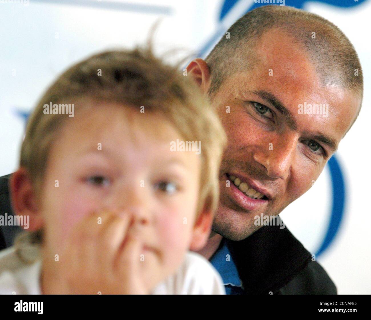 La jugadora francesa del Real Madrid Zinedine Zidane posó con Yan, un niño de nueve años de edad que sufre de Leucodistrofias, en una promoción de libros benéficos en la clínica de Genolier en Genolier, Suiza, el 10 de mayo de 2004. El libro recientemente presentado 'Tous en canastas' (traducido aproximadamente 'unir en la lucha') reúne a 85 portaits de actores y deportistas famosos posando con el mismo par de botas de Zinedine Zidane. El beneficio del libro será donado a la Asociación Europea de Leucodistrofías, una organización patrocinada por Zinedine Zidane. Las leucodistrofias son enfermedades genéticas que destruyen lo central Foto de stock