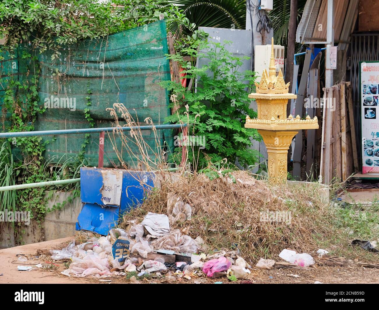 Camboya, Siem Reap 12/08/2018 un pequeño santuario budista entre los montones de basura en una calle de la ciudad, un basurero cerca de un objeto religioso Foto de stock
