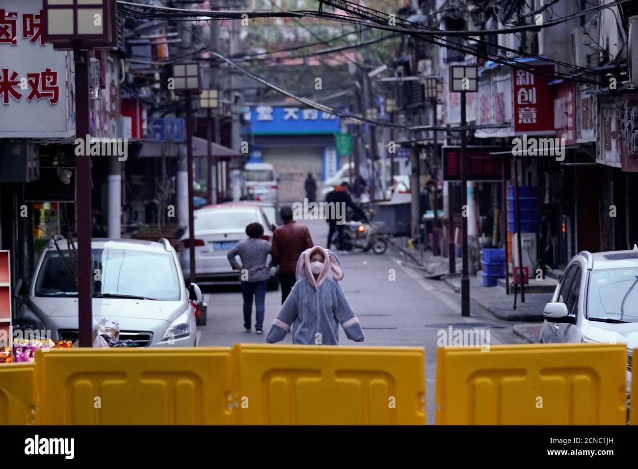 Una mujer que lleva una máscara facial y un pijama es vista en una zona residencial bloqueada por barreras en Wuhan, provincia de Hubei, el epicentro del brote de la enfermedad coronavirus de China (COVID-19), el 1 de abril de 2020. REUTERS/Aly canción Foto de stock