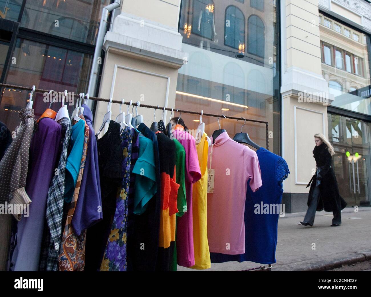 Una mujer pasa por delante de una exhibición de camisas baratas, en frente a las tiendas de ropa de diseño McQueen y Stella McCartney en Moscú el 27 de marzo