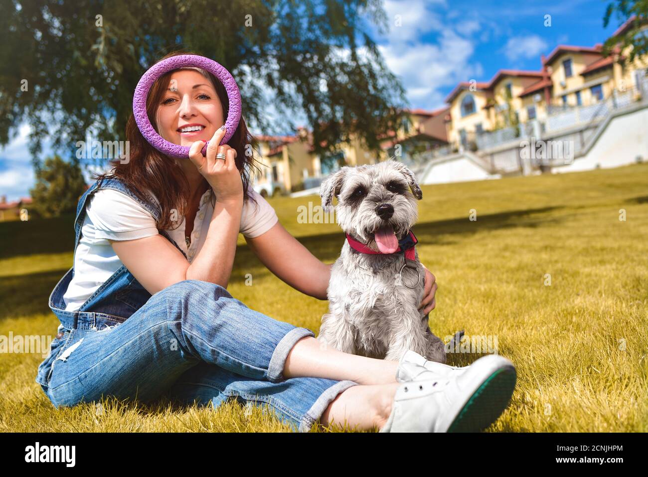Mujer caucásica alegre jugando con su amado perro en el parque. El concepto de amor a los animales. Mejores amigos. Perro raza Schnau Foto de stock