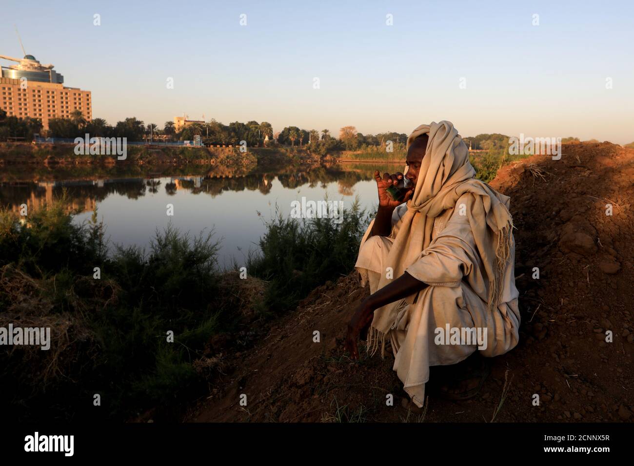 Mohamed Ahmed al Ameen, de 55 años, un fabricante de ladrillos, bebe una taza de té mientras se sienta en el borde del Nilo Azul cerca de una fábrica al aire libre en la isla Tuti, Jartum, Sudán, 14 de febrero de 2020. "Considero que el Nilo es algo con lo que nunca he estado, desde que nací", dijo Ameen. "Yo como de ella, yo granja con ella. ¿también extrajo estos ladrillos de él? Toda mi fuente de ingresos proviene del Nilo." REUTERS/Zohra Bensemra BUSCA 'BENSEMRA NILE' PARA ESTA HISTORIA. BUSQUE "IMAGEN MÁS AMPLIA" PARA TODAS LAS HISTORIAS. Foto de stock