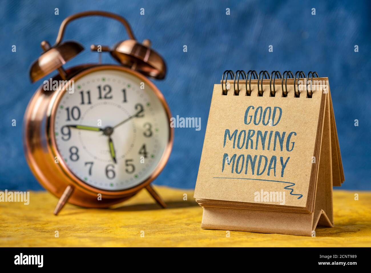 Buenos días Lunes - escritura alegre un cuaderno espiral con un reloj  despertador, nueva semana en el concepto de oficina Fotografía de stock -  Alamy