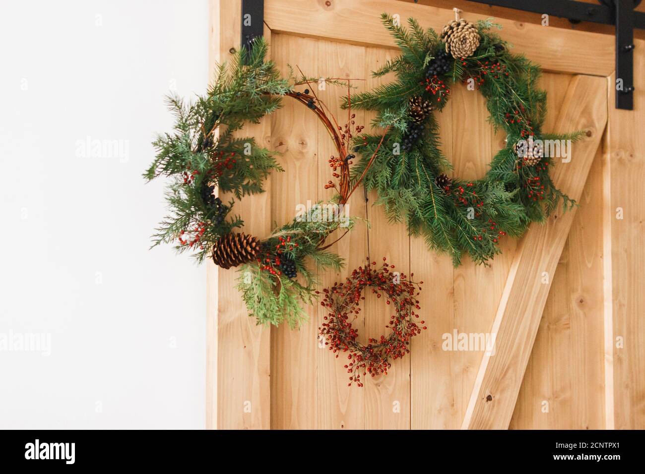 Flores de Navidad rústica en la puerta de madera interior, decoración  festiva de vacaciones. Flores naturales creativas y diferentes guirnaldas  de Navidad colgando en el elegante rural Fotografía de stock - Alamy