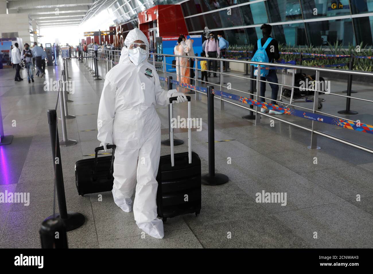 Una persona que lleva equipo de protección personal (PPE) lleva equipaje en  el aeropuerto internacional Indira Gandhi (IGI), después de que el gobierno  permitió que se reanudaran los servicios de vuelos nacionales,