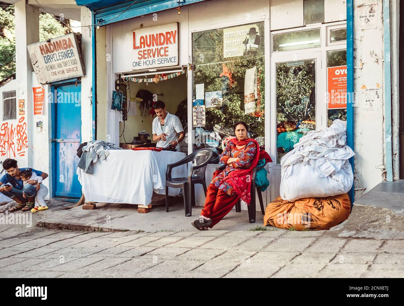 Manali, Himachal Pradesh, India - 27 de agosto de 2016: Mujer como cliente del servicio de lavandería de la calle espera una lavandería en Manali, India. Foto de stock