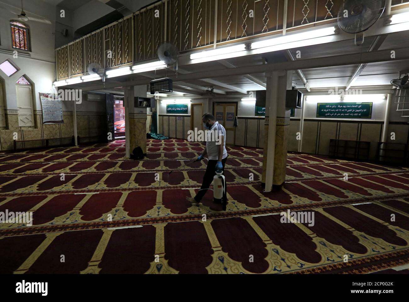 Un voluntario que lleva una máscara pulveriza desinfectante dentro de una mezquita, ya que está preparado para la oración después de ser reabierto, después del brote de la enfermedad del coronavirus (COVID-19), en el Cairo, Egipto, 26 de junio de 2020. REUTERS/Mohamed Abd el Ghany Foto de stock