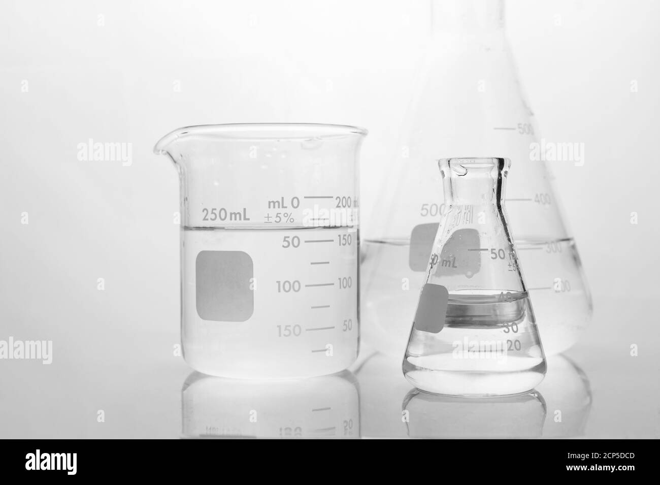 agua clara en vaso de precipitado y matraz en ciencia médica blanca antecedentes de laboratorio Foto de stock